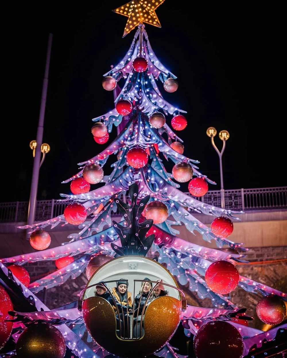 Christmas tree ride lit at night in a public plaza